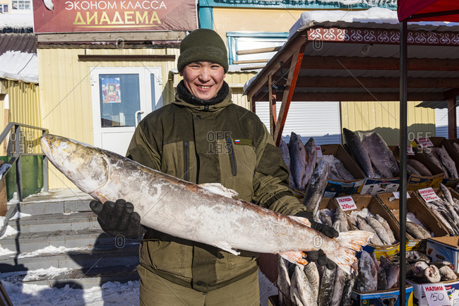 March 3, 2020: Local fish seller holding a huge frozen fish, Fish and meat market, Yakutsk, Sakha Republic (Yakutia), Russia, Eurasia