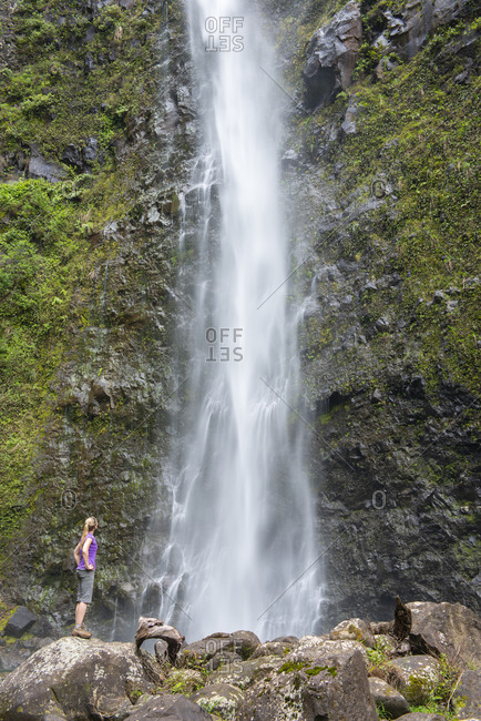 Hiker admiring a waterfall along the famous Kalalau Trail, along Kauai's Na Pali Coast, Kauai, Hawaii, United States of America, North America