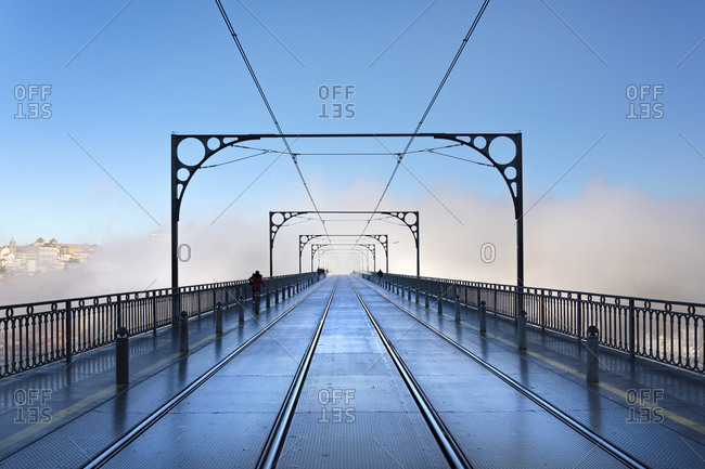 Tram tracks in the early morning mist running over Dom Luis I Bridge in Porto, Portugal, Europe