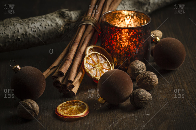 Christmas decoration with tea light candle- christmas tree balls- cinnamon sticks- slices of dried oranges and walnuts on wooden table- studio shot