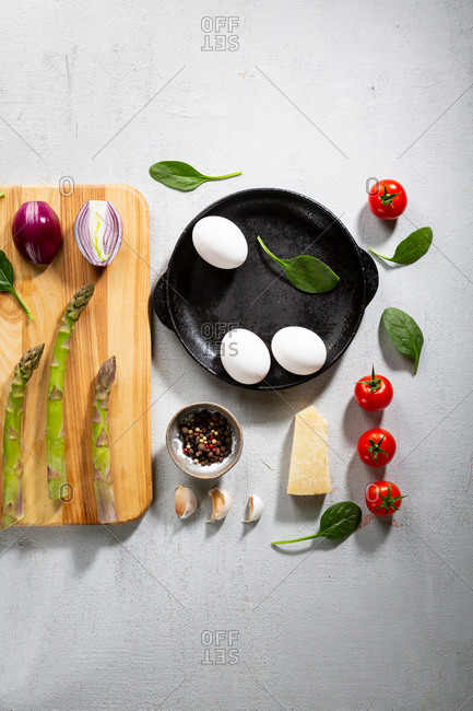 Overhead view of fresh frittata ingredients on light surface
