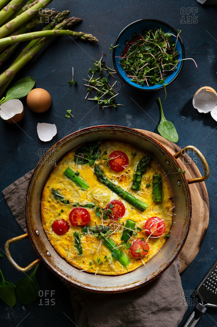 Overhead view of spinach and asparagus frittata on dark surface