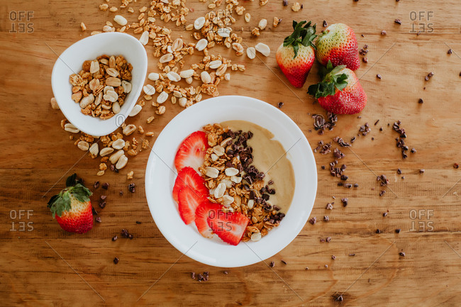 Closeup bowl of tasty sweet puree with strawberry and chocolate complemented with peanuts and walnuts and served for breakfast