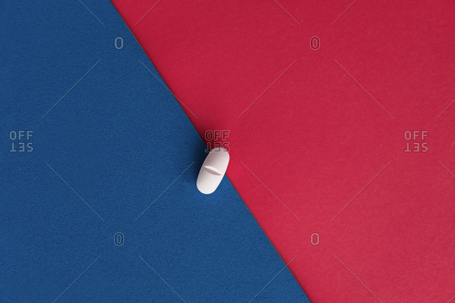 Top view of prescription pill for flu treatment placed on red and blue sheets of paper