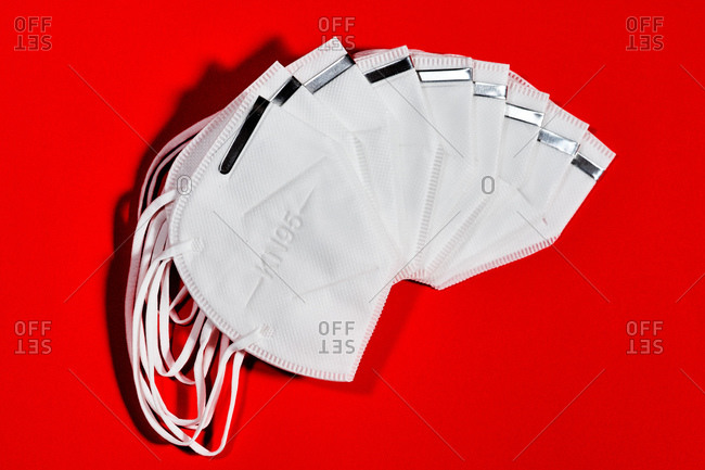 group of white masks fanned out with reusable KN95 protection index for virus protection on red background