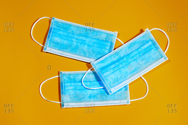 94/5000group of three blue single-use masks for virus protection on yellow background