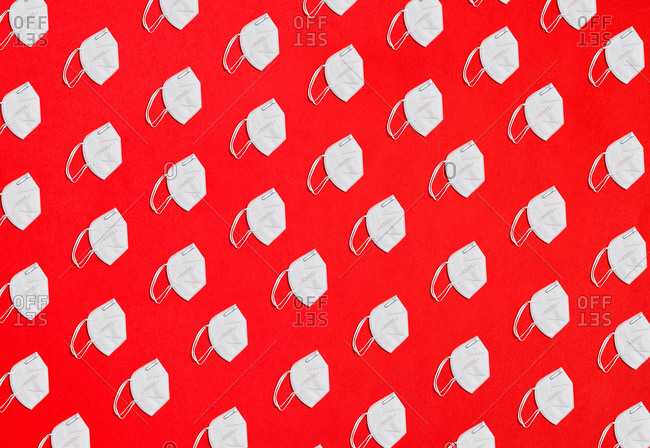 Collage of many KN95 factor protection masks on a red background overhead view in diagonal distribution