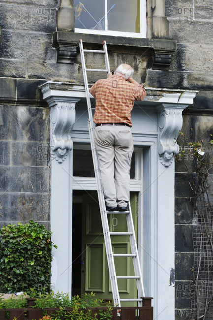 Senior anonymous man repairing door of old mansion