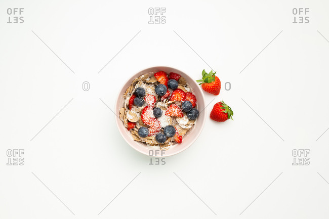 Top view of delicious dish with strawberries and blueberries placed on top of white table