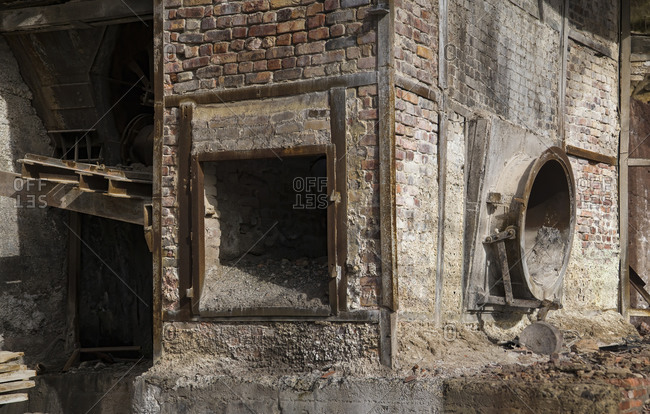 Dirty brick structure with trash located inside shabby workshop of derelict industrial facility