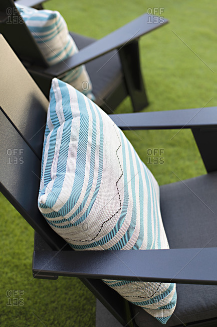 Black Adirondack chairs with pillows on green lawn