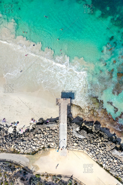 Aerial view of a jetty with the sea, some swimmer, and waves in Perth, Western Australia, Australia
