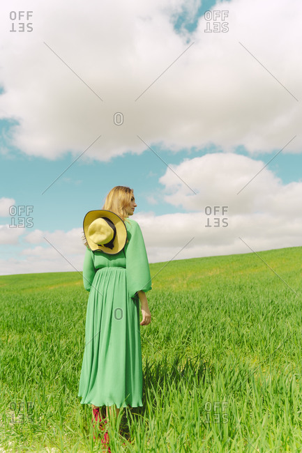 Back view of woman wearing green dress standing on a field