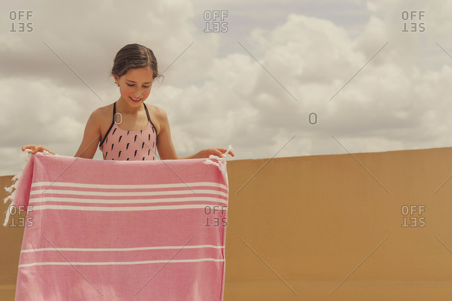 Portrait of smiling girl with blanket wearing swimsuit on roof terrace