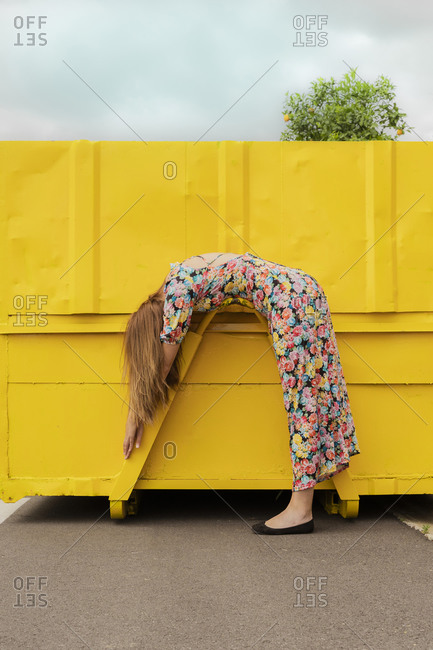 Woman in flower dress bending over attachment of yellow container