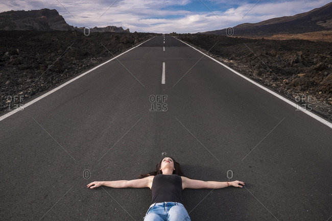 Spain- Tenerife- woman lying on an empty road with outstretched arms