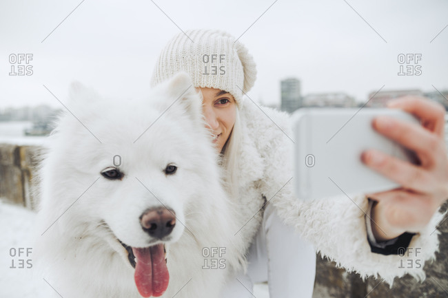 Serbia- Petrovaradin- white dressed woman taking selfie with white dog in winter