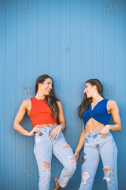Laughing twins in front of blue wall