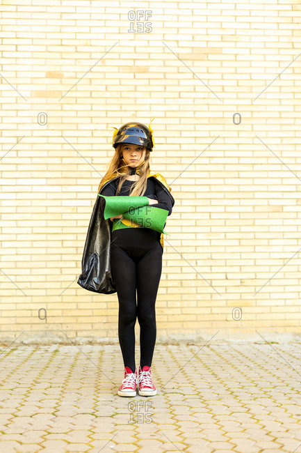 Girl in super heroine costume posing at brick wall