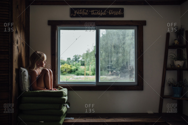 Girl sitting on chair by window at home