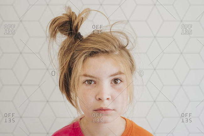Young girl with hair in a messy bun looking at camera