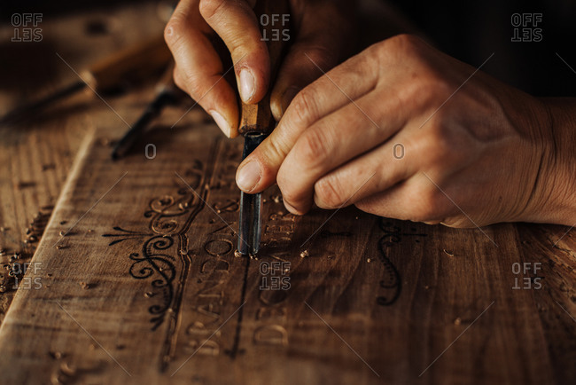 Close up process of decorative wood engraving using hand tools
