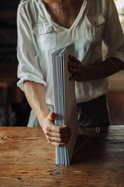 Woman handling a stack of sheets for binding, handmade book production