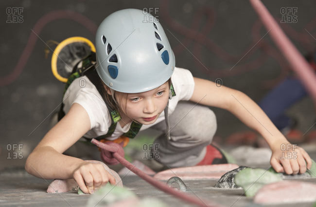 Young girl climbing at indoor climbing wall in England / UK