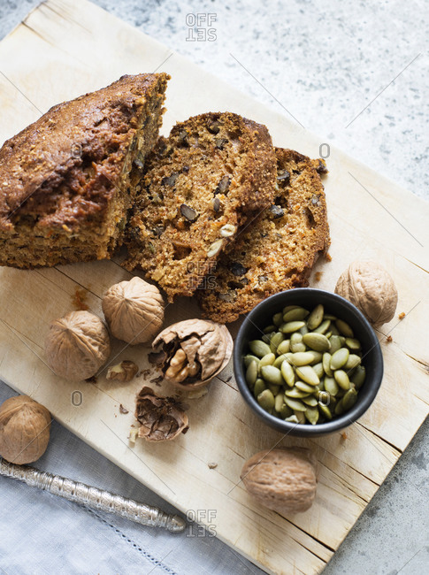 Still life of walnut and pumpkin seed cake sliced on cutting board, overhead view