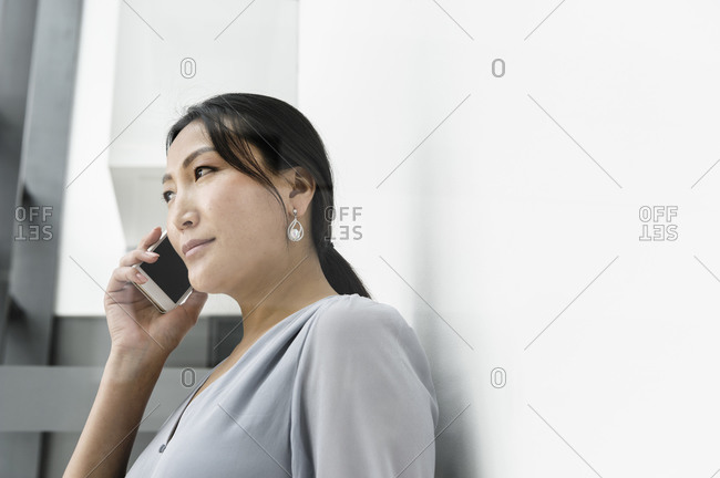 Businesswoman using smartphone against white wall in office