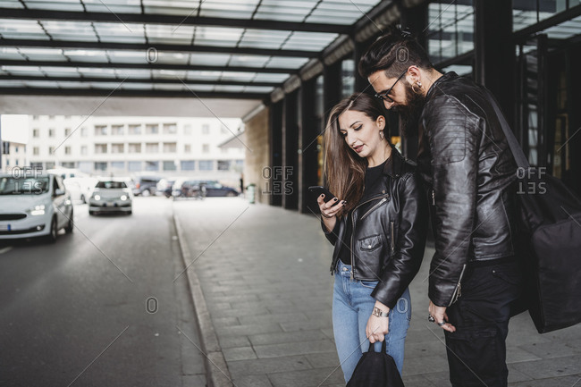 Couple using smartphone outside station