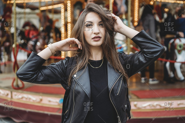 Woman touching hair and posing in front of carousel