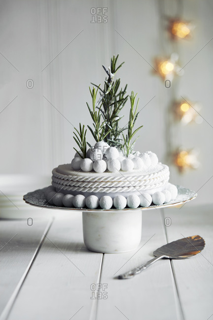 Close up of richly decorated Halloween cake with white icing and rosemary sprigs.