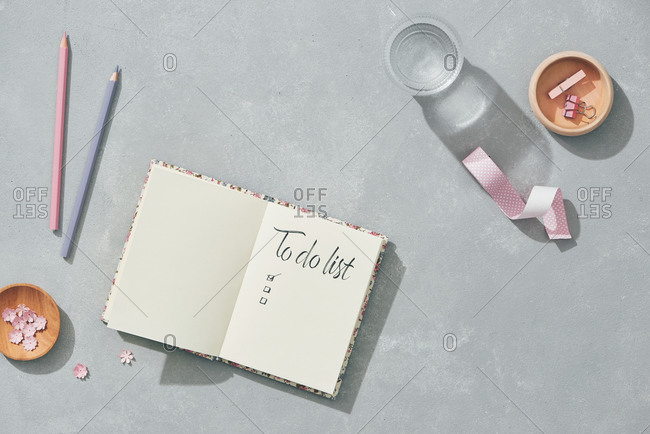 Creative flat lay mockup design of workspace desk with blank notebook, glass of water, stationery with copy space background