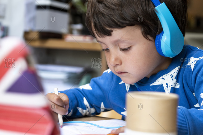 Young boy doing distance learning on a tablet with headphone