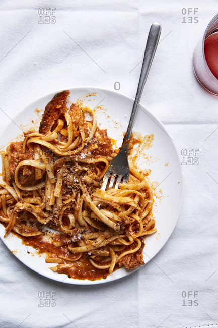Fresh pasta in a tomato sauce with croutons served in a plate and a glass of wine on a white linen cloth,