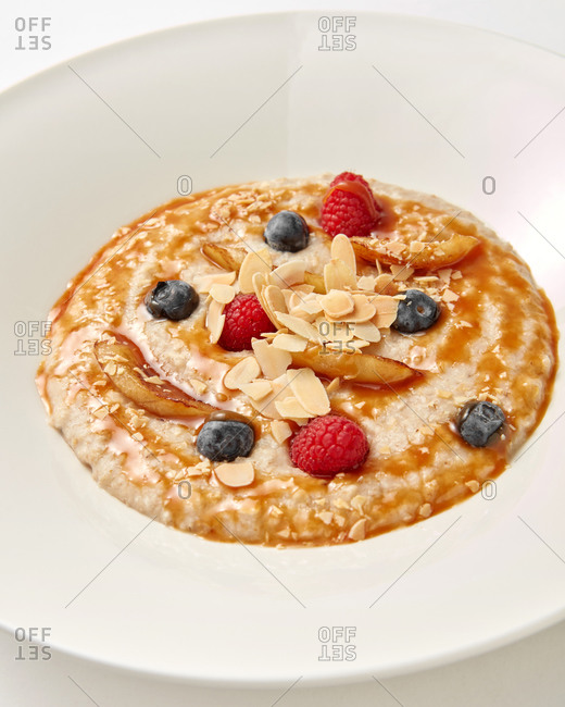 Healthy diet breakfast from freshly cooked porridge with natural organic berries and sweet honey in a ceramic plate, copy space.