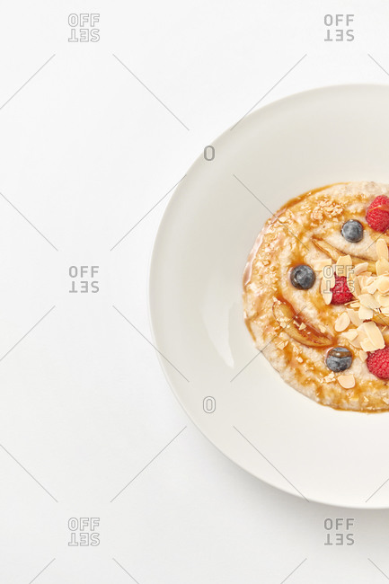 Half ceramic white plate of homemade freshly cooked porridge with natural organic berries and sweet honey in a ceramic plate, copy space.