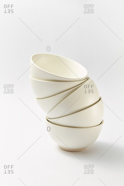 Tableware set from stack of white porcelain clean empty soup bowls on a light grey background, copy space.