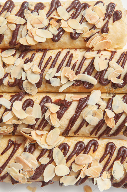 Dessert background from homemade freshly cooked spring rolls with top from chocolate and almond chip. Close up top view.