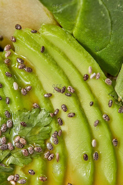 Natural vegetable vegan background. Macro view of freshly cooked homemade salad from organic natural ingredients - sliced avocado, greenery and seeds.