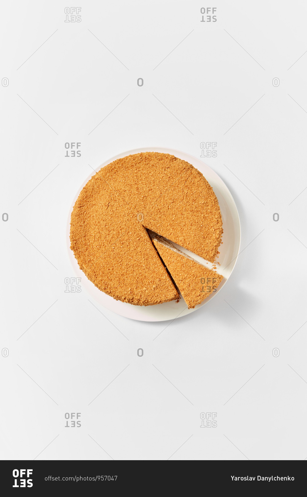 Top view of the whole homemade freshly baked honey cake with cut piece of delicious sweet dessert on a ceramic plate on white background, copy space.