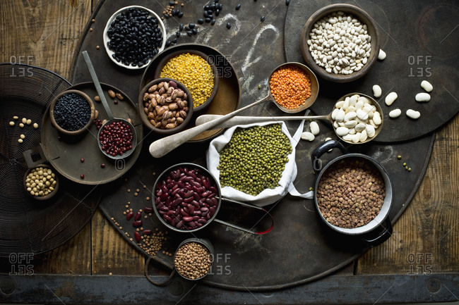 Bowls with various beans and lentils on rustic baking sheet