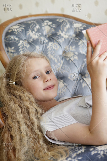 Portrait of a girl lying on a couch reading a book