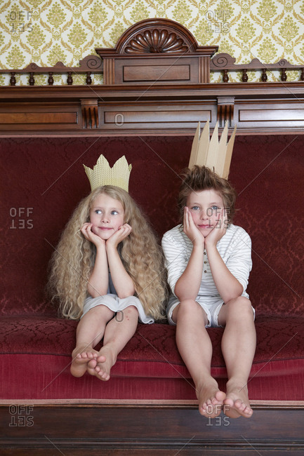 Boy and girl sitting on a couch wearing cardboard crowns
