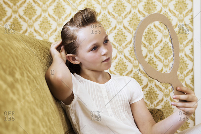 Portrait of girl on a couch looking in cardboard mirror