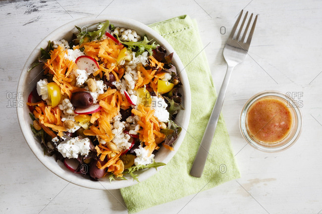 Bowl of vegetarian salad with goat cheese- barley- radishes- olives- carrots- tomatoes and figs