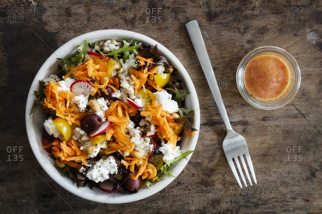 Bowl of vegetarian salad with goat cheese- barley- radishes- olives- carrots- tomatoes and figs