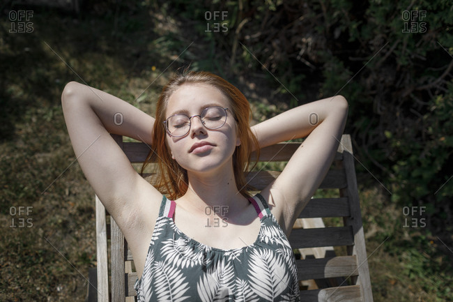 Portrait of young woman sunbathing on deckchair in garden