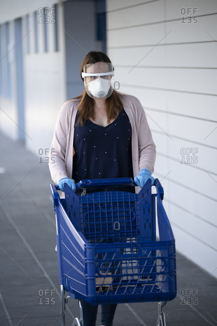 Woman walking while pushing shopping cart outside supermarket during COVID-19 pandemic